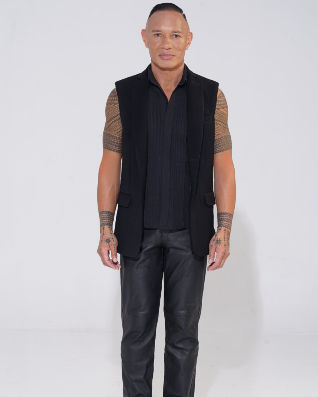 Black tailored sleeveless jacket with two-button front on male model with Endemann leather pants and black sleeveless shirt