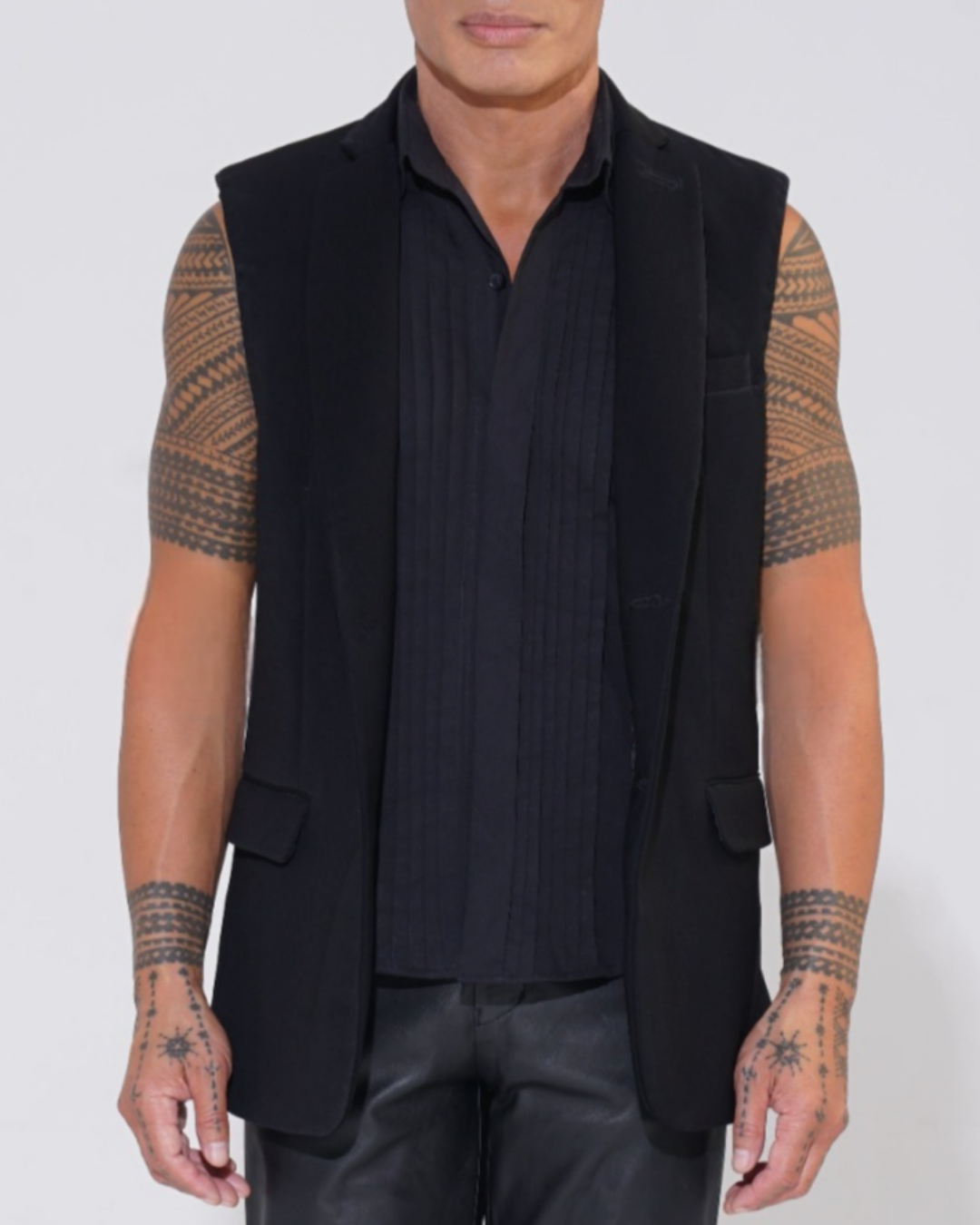 Black tailored sleeveless jacket with two-button front on male model with Endemann leather pants and black sleeveless shirt