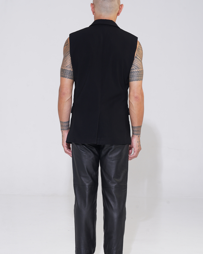 Black tailored sleeveless jacket with two-button front on male model with Endemann leather pants back view