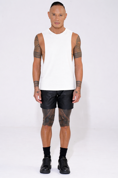 Man wearing a white sleeveless tank top with deep sides with arm tattoos 